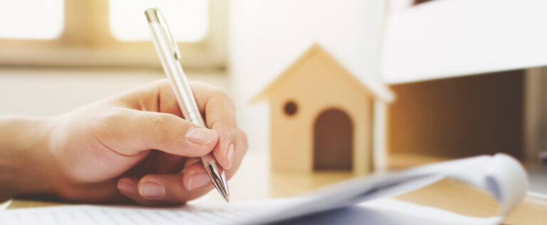 Close up hand of man signing signature loan document to home ownership. Mortgage and real estate property investment