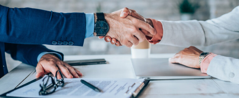 Cropped shot of unrecognizable business persons shaking hands after signing a contract. Business people shaking hands in the office.